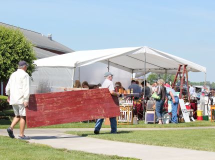 Shoppers carrying larger red barn door at the Shipshewana Antique & Vintage Market Festival in Indiana